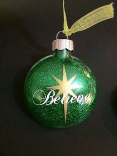 a green christmas ornament with the word believe on it and a gold star