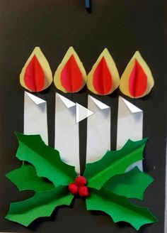 an origami christmas decoration with candles and holly leaves