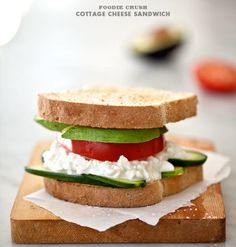 a sandwich with cucumber, tomato and feta cheese on a cutting board