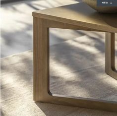 a wooden table sitting on top of a carpeted floor next to a bowl of fruit