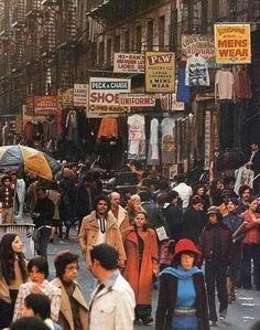 many people are walking down the street with umbrellas in their hands and signs above them