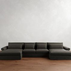 a large gray couch sitting on top of a wooden floor next to a white wall