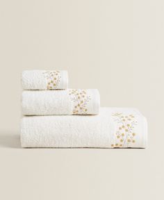 three towels stacked on top of each other in front of a white wall with yellow flowers