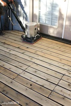 a man is using a floor sander on a wooden deck in front of a house