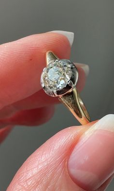 a close up of a person's hand holding a ring with a diamond in it