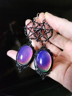 Our latest design is inspired by moody witches.  We've taken black pentacle charms and posited them up with gorgeous color changing mood cabochons made of glass set in an ornate black frame.  Perfect witchy goth earrings! 🥰  - Glass 25x18mm mood color changing with heat cabochons - black pewter pentacle and materials - Stainless steel earrings hooks with rubber backs included. Gothic Black Hypoallergenic Earrings, Gothic Black Cabochon Jewelry, Mystical Black Metal Jewelry, Black Gothic Cabochon Jewelry, Mystical Nickel-free Black Jewelry, Mystical Black Nickel-free Jewelry, Black Fantasy Style Pierced Earrings, Handmade Black Fantasy Earrings, Black Fantasy Earrings