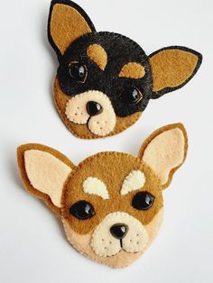 two felt dog head brooches with black eyes and brown ears on white background