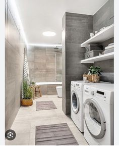 a washer and dryer in a bathroom with grey tiles on the walls, along with shelves