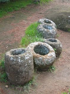 four large rocks sitting on top of a dirt field