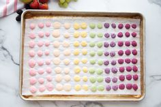 a baking tray filled with colorful cookies and fruit on top of a marble countertop