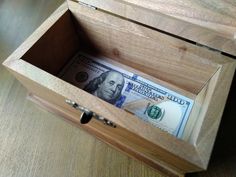 a wooden box filled with money on top of a table