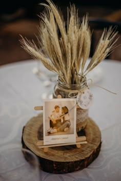 an old photo is placed in a glass jar on a wood slice with some dried grass