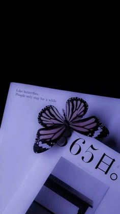 a butterfly sitting on top of a book with the number 65 below it's wing