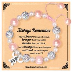 a bracelet with pink pearls and swarongs on it, says always remember