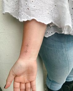 a woman's hand with a small star tattoo on the middle of her left arm