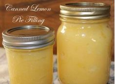 two jars filled with yellow liquid sitting on top of a cloth covered table next to each other