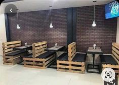 tables and chairs made out of wooden pallets in front of a brick wall with a flat screen tv