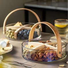 two baskets filled with nuts and cheese on top of a table next to other food items