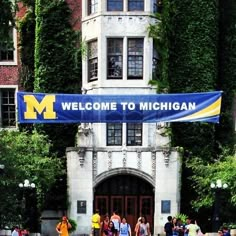 people are standing in front of the michigan university welcome to michigan banner on an old building