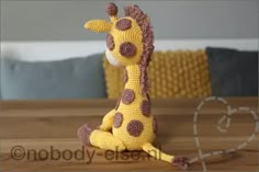 a crocheted giraffe sitting on top of a wooden table