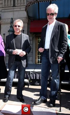 two men standing next to each other in front of a building