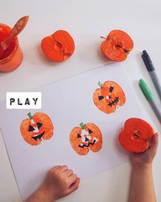 a child's hand is painting pumpkin faces on a paper with markers and pencils