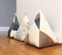 three teepee shaped pillows sitting on top of a wooden floor next to a wall