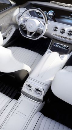 the interior of a sports car with white leather and black trims, including steering wheel