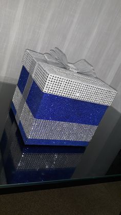 a blue and white gift box sitting on top of a glass table next to a wall