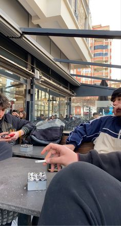 two men sitting at an outdoor table playing cards