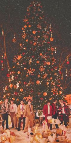 a group of people standing in front of a christmas tree