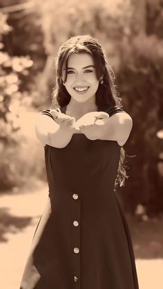 a woman in a black dress is posing for a photo with her arms folded out