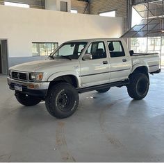 a white pick up truck parked in a garage next to a building with large windows