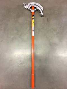 an orange and white baseball bat sitting on top of a cement floor next to a hammer