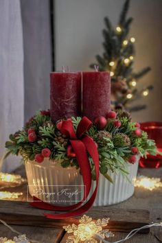 two red candles are sitting in a white bowl with holly and berries on it, surrounded by christmas lights