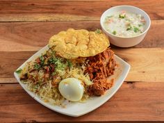 a white plate topped with food next to a bowl of soup