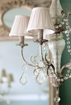 a chandelier with two lamps on top of it and a mirror in the background