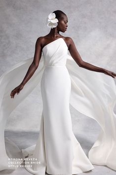 a woman in a white dress with a flower on her head and flowing fabric around her shoulders