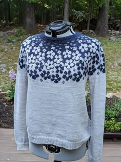 a mannequin wearing a blue and white sweater with flowers on it's chest