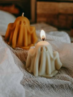 two candles sitting on top of a bed next to each other