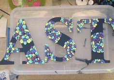 the letters are made out of plastic and have flowers painted on them in different colors