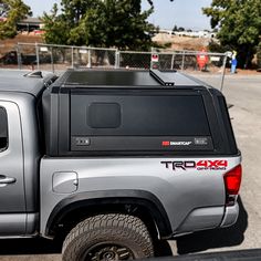 the back end of a silver truck parked in a parking lot next to a fence