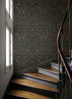 a stair case next to a window in a room with floral wallpaper on the walls