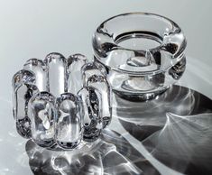 two clear glass objects sitting on top of a white table with shiny silver circles around them