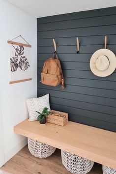 a wooden bench sitting next to a wall with two hats on it's hooks