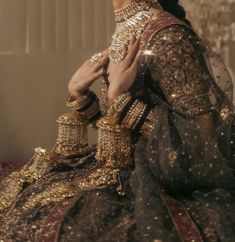 a woman dressed in an elaborate gold and black outfit with her hands on her chest