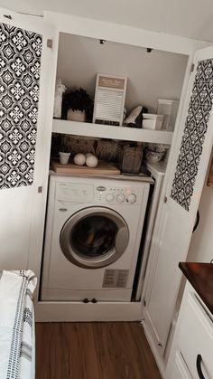 a washer and dryer in a small room next to a window with black and white curtains