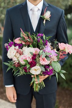 a man in a suit holding a bouquet of flowers