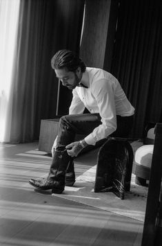 a man sitting on top of a suitcase in a living room next to a window