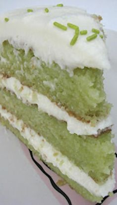 a piece of green cake with white frosting and sprinkles on top